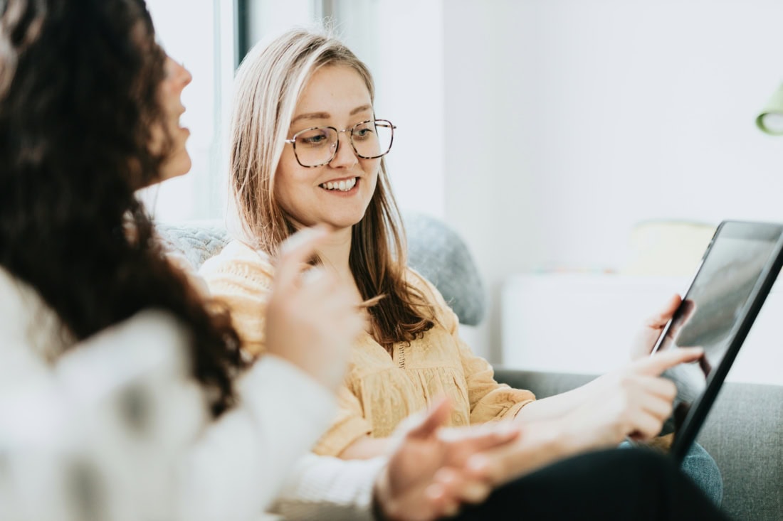 Vrouw wijst naar laptopscherm om iets te tonen aan een andere vrouw